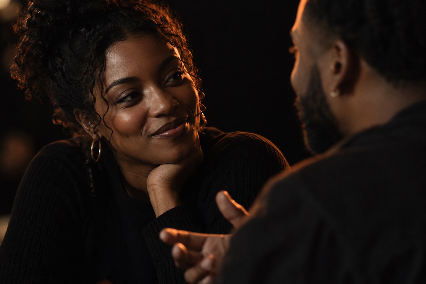 Conceptual close-up of two people listening and talking in warm light